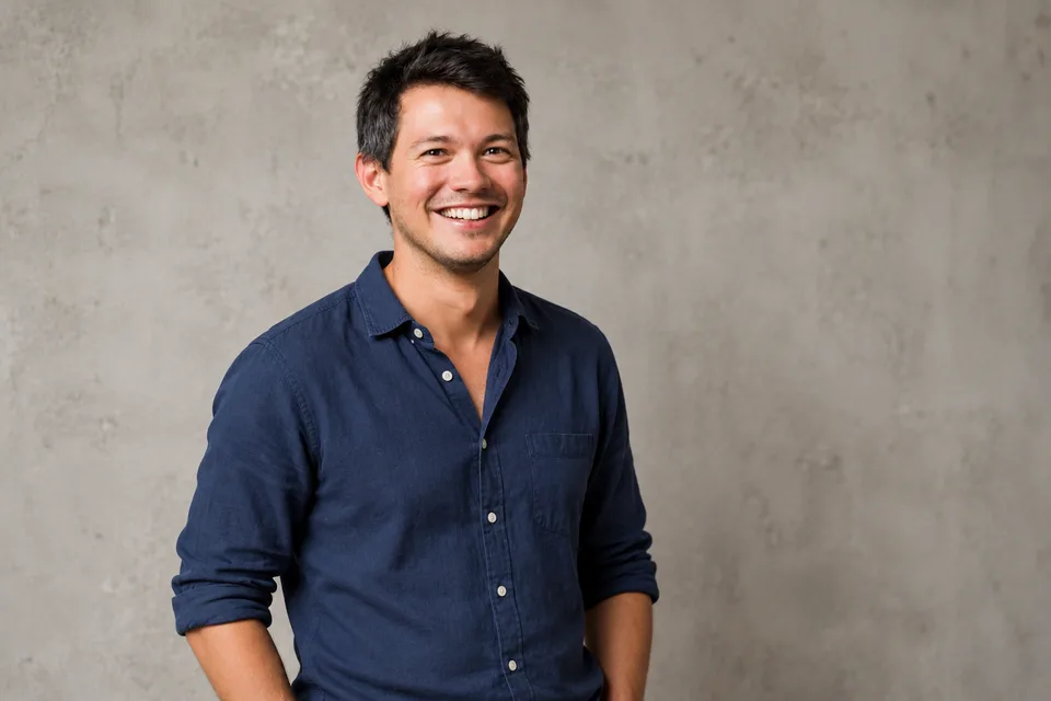 Portrait de Mathias Salanon, chemise bleue, souriant devant un mur gris