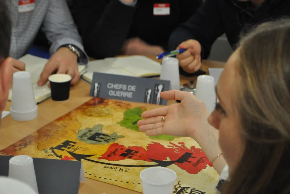 Participants réunis autour d'une table pour un jeu de recrutement, archive Opopoï